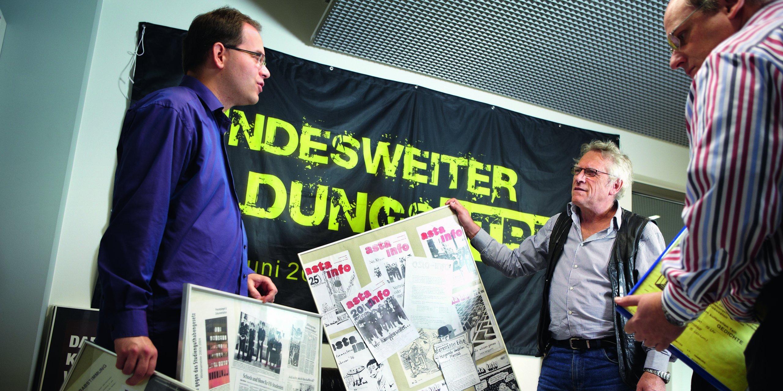 Herr Finas, Herr Niemann, Herr Ripper mit Plakaten des AStA