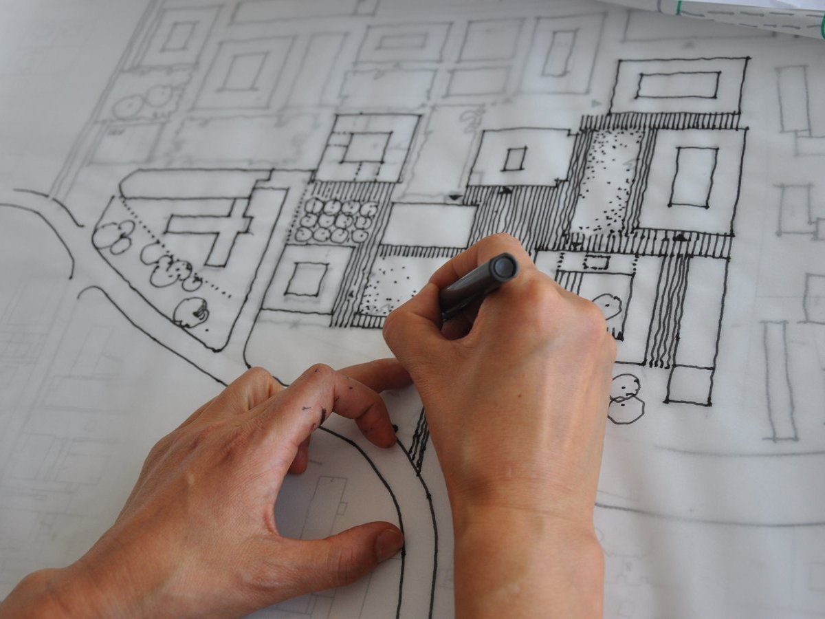Hände mit Stift beim Zeichnen eines Architekturplanes