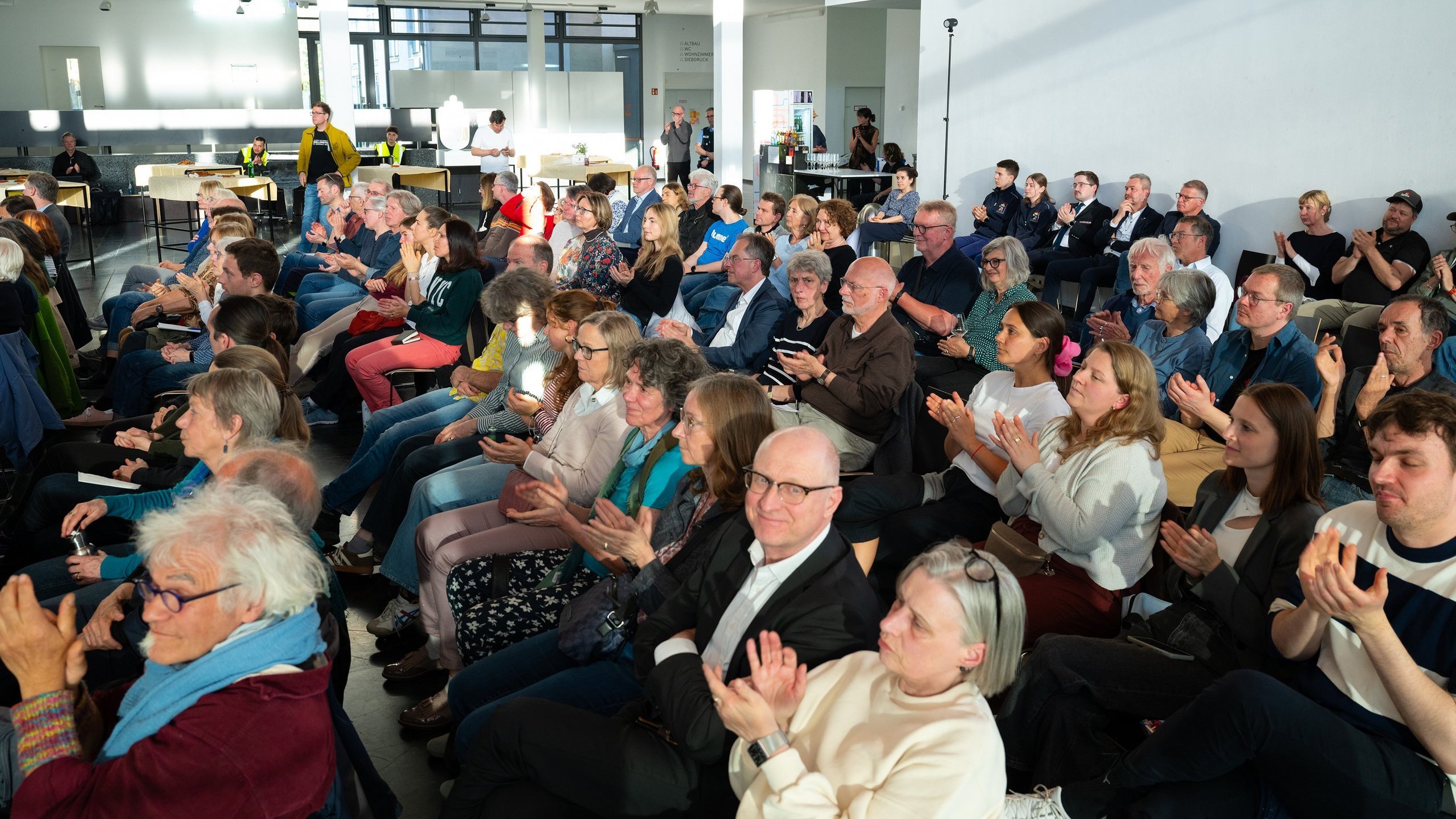 Die Gäste im Foyer applaudieren den Vortragenden