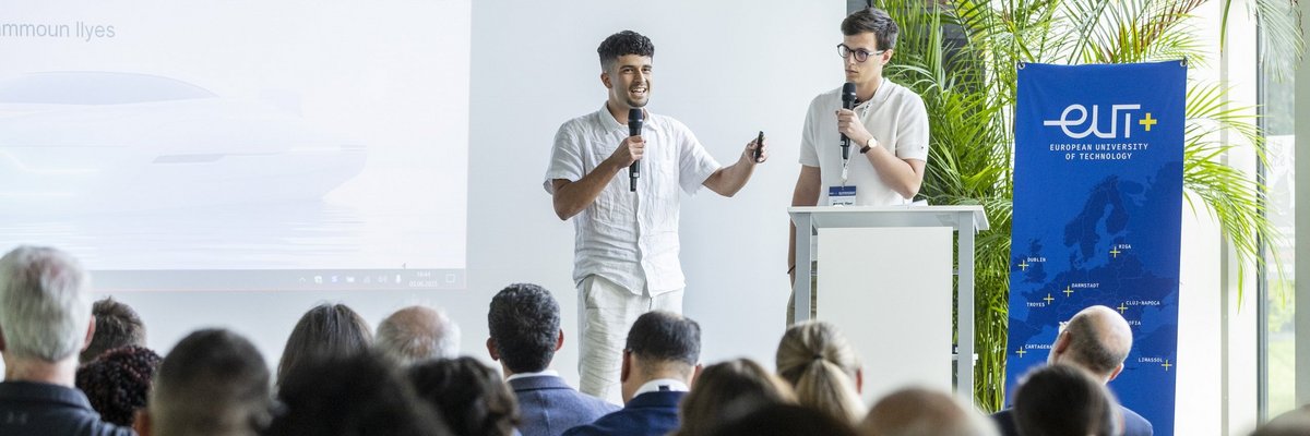 Junger Student auf dem Podium m Café Glaskasten vor großem Publikum