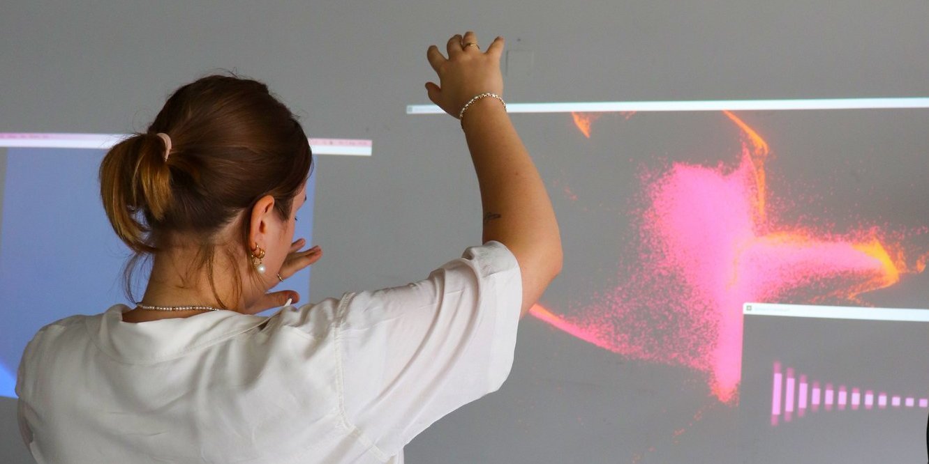 Person gestikulierend vor Notebook-Bildschirmen und Leinwand