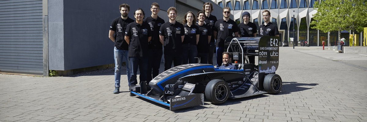 Das Formula Student-Team der h_da an seinem neuen E-Rennwagen F 25. Im Wagen sitzt Prof. Dr. Florian van de Loo, der das Team betreut. Lucas Wagner (4 vl) und Michelle Peters (5vl) sind aus der studentischen Teamleitung. Foto: h_da/Jens Steingässer