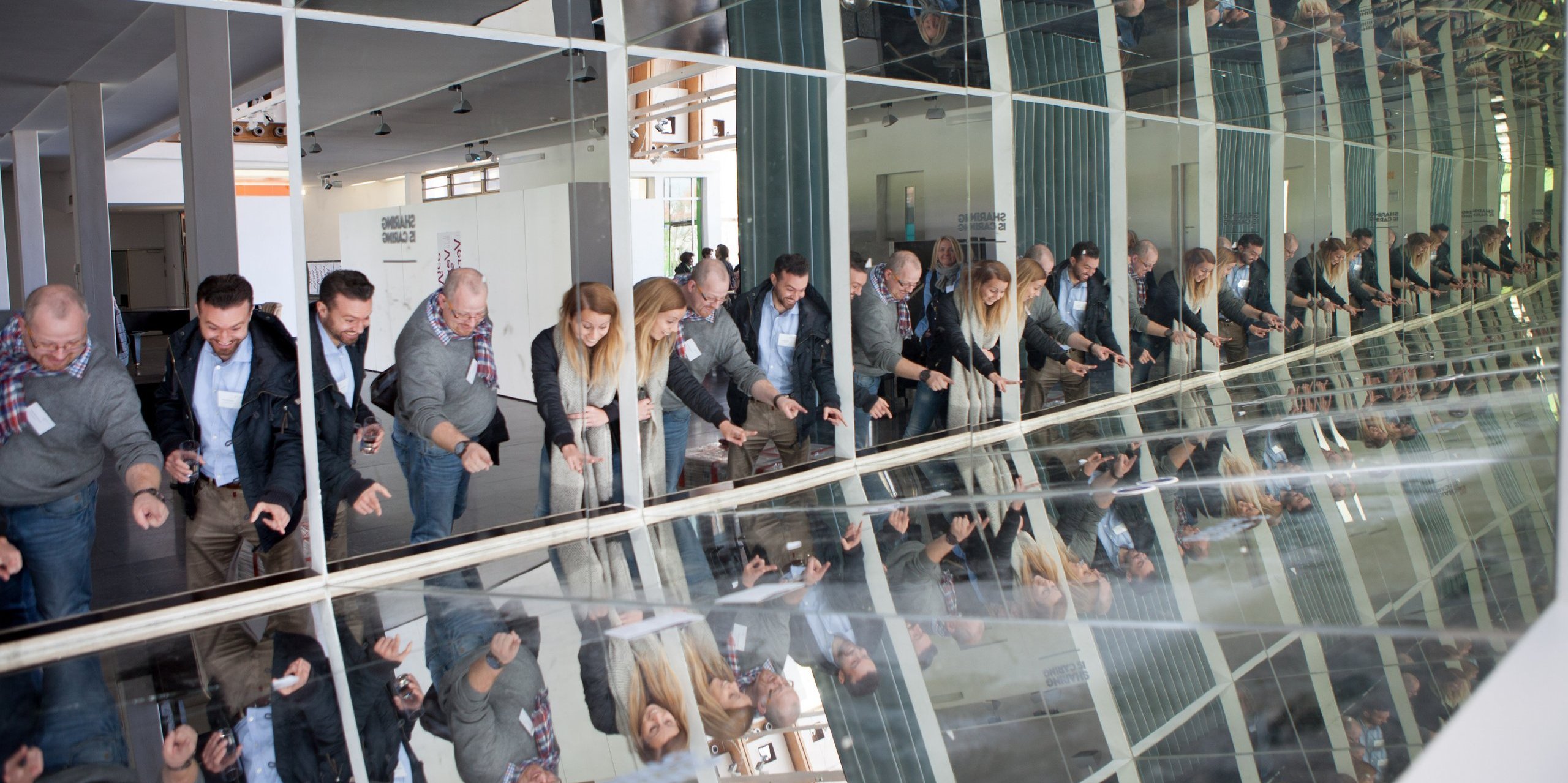 [Translate to English:] Besucher:innen der h_da blicken in eine spiegelnde Fensterfront