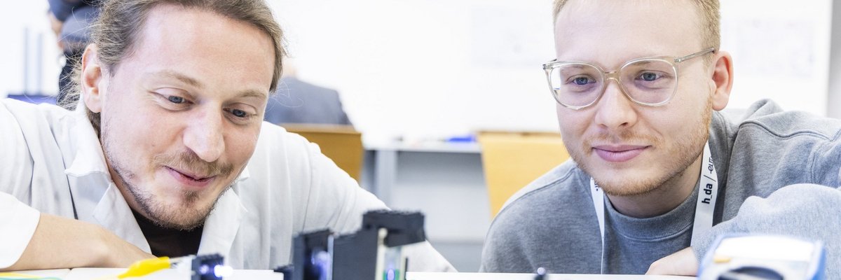 Zwei junge Männer knien vor eine Tisch und experimentieren mit Lego