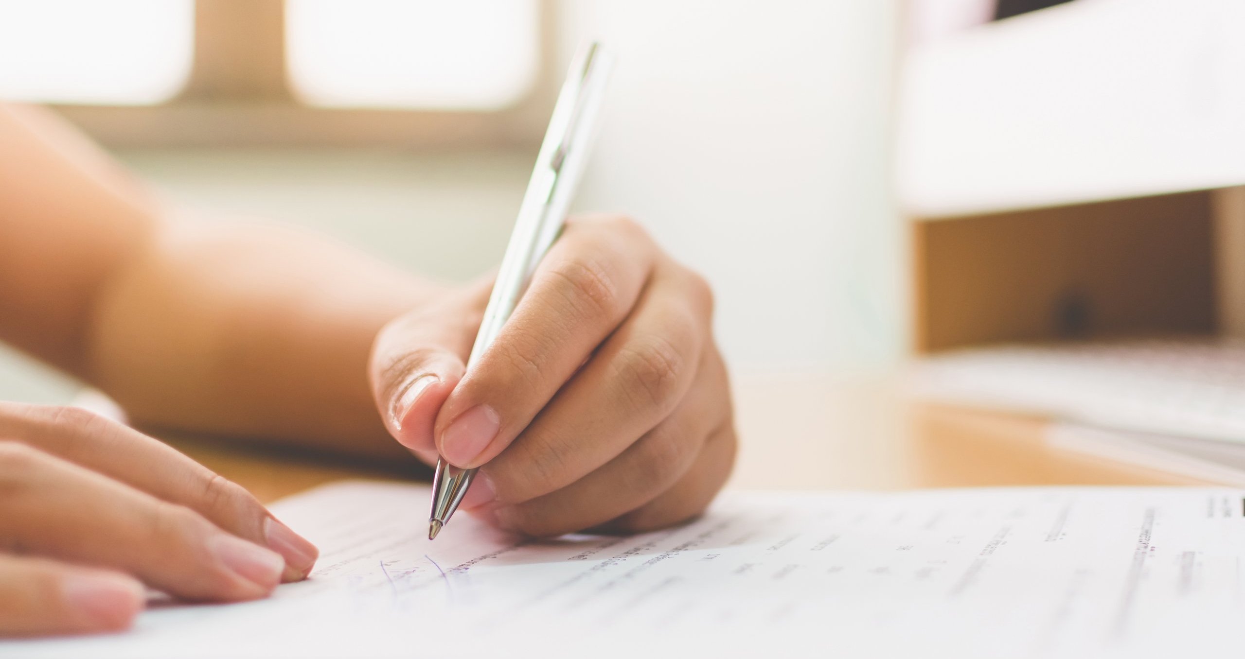 Hand einer Person, die mit einem Stift einen Brief schreibt