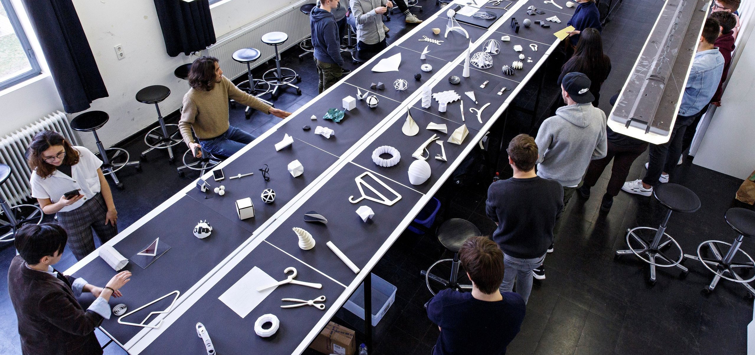 several people in a room with models of consumer goods hanging from the ceiling