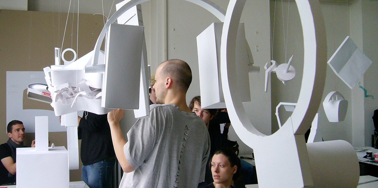 several people in a room with models of consumer goods hanging from the ceiling