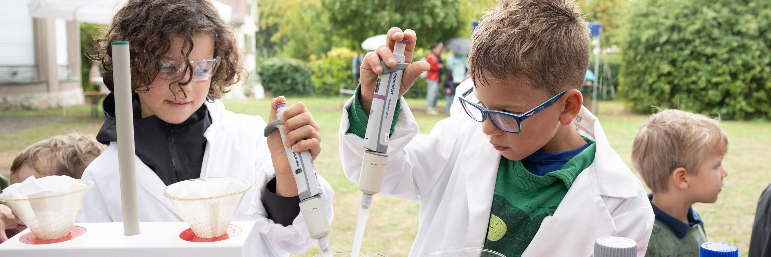 Kinder in Laborkitteln beim Experimentieren 