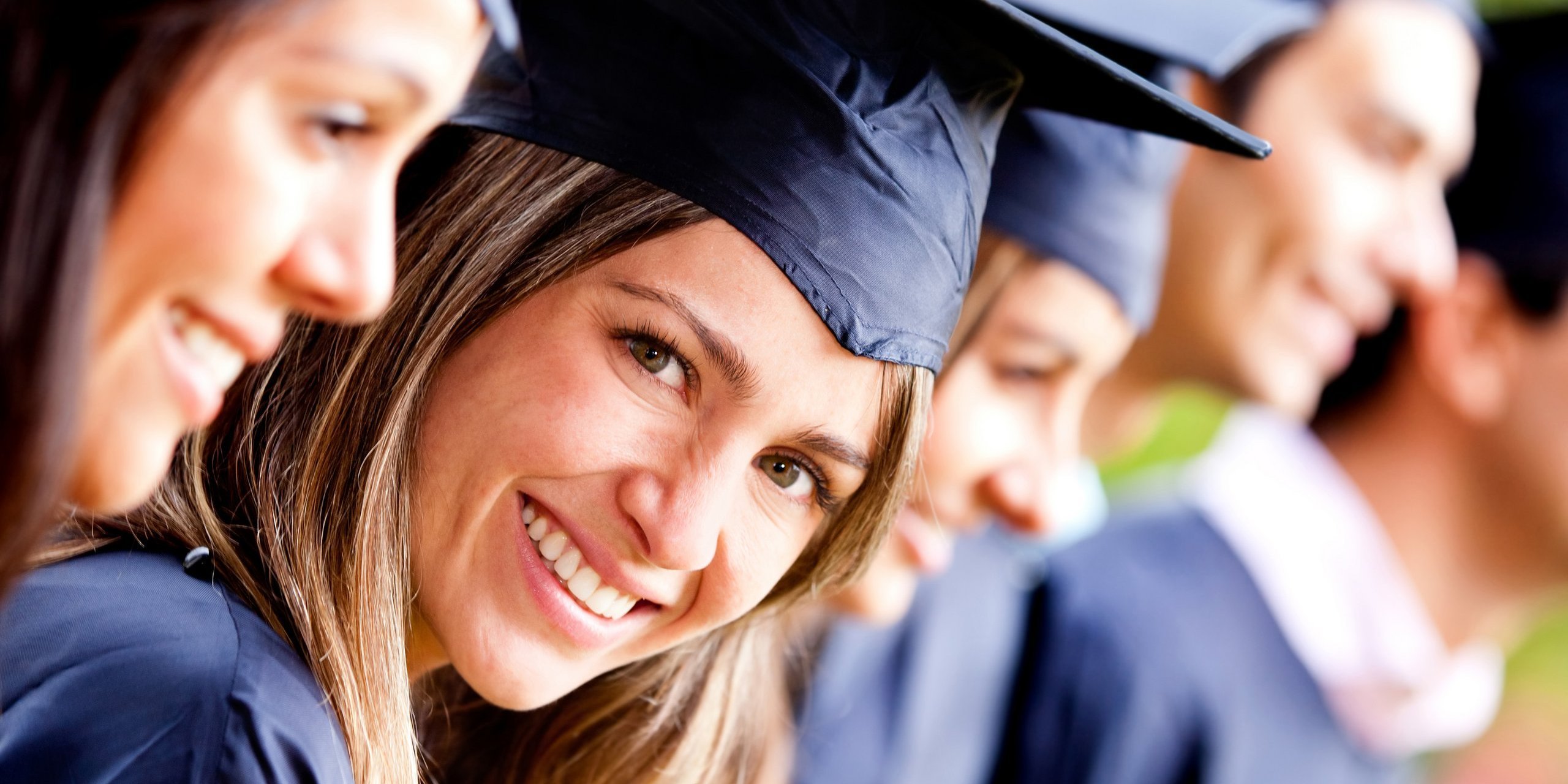 Gruppe junger Menschen auf einer Absolventenfeier ein Person lächelt in die Kamera
