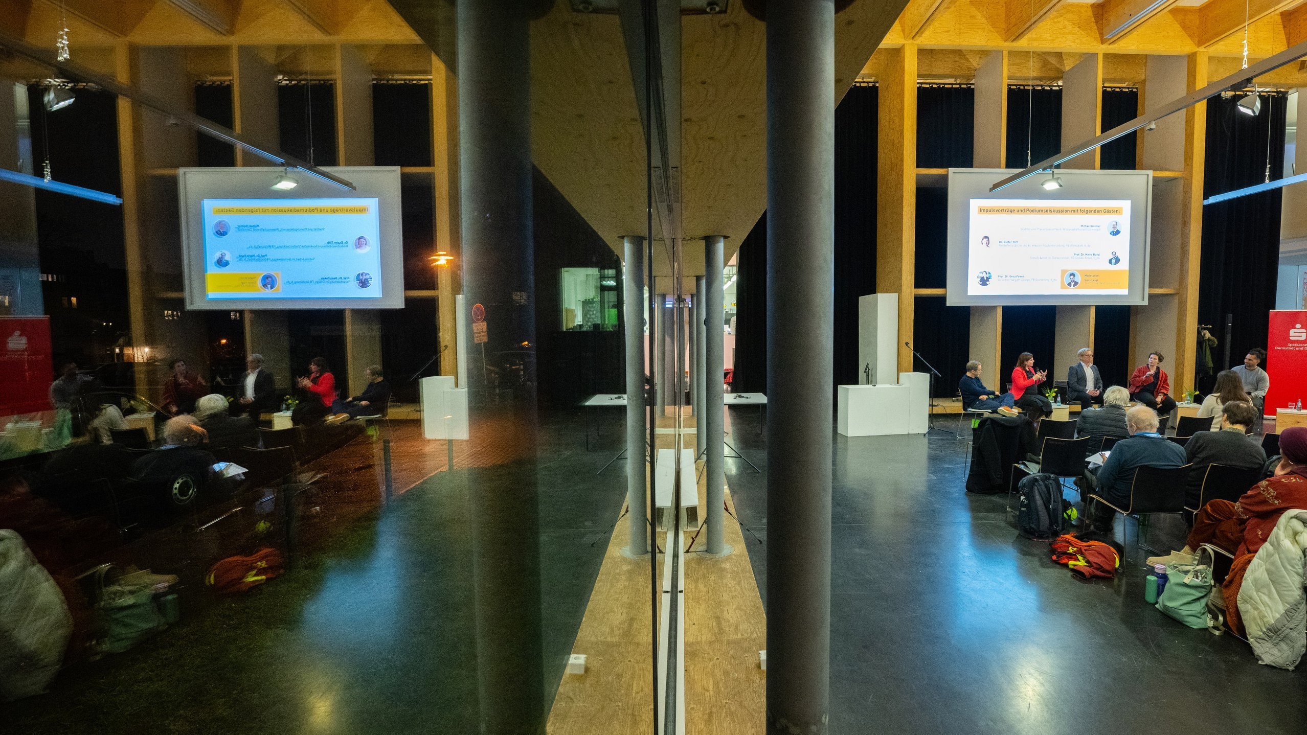 Symmetrische Aufnahme, in der sich das Auditorium in der Glasfassade spiegelt