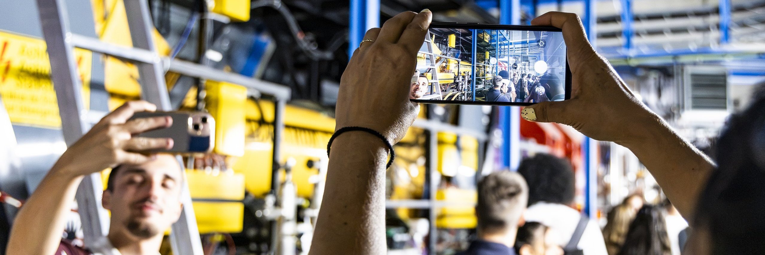 Studierende machen Fotos und Selfies in einer Laborhalle