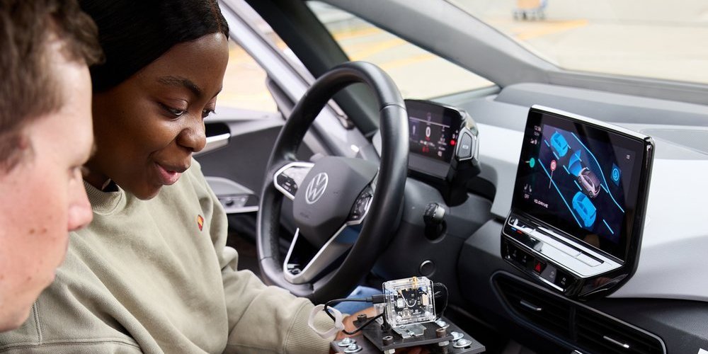 zwei Personen betrachten auf den Vordersitzen eines Autos sitzend technisches Gerät
