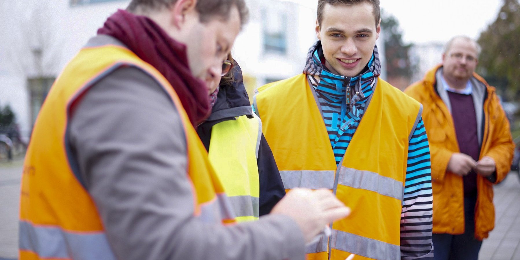 Gruppe von Studierenden des Bauingenieurwesens der Hochschule Darmstadt trägt reflektierende Warnwesten und steht im Freien vor einem Gebäude.