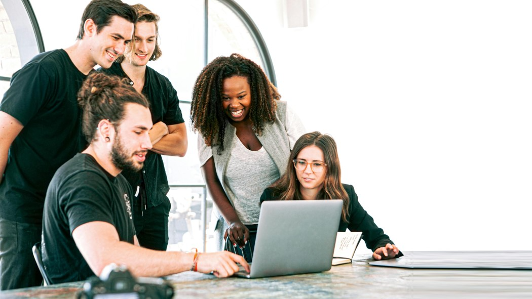 Eine Gruppe von gut gelaunten Menschen plant am Laptop