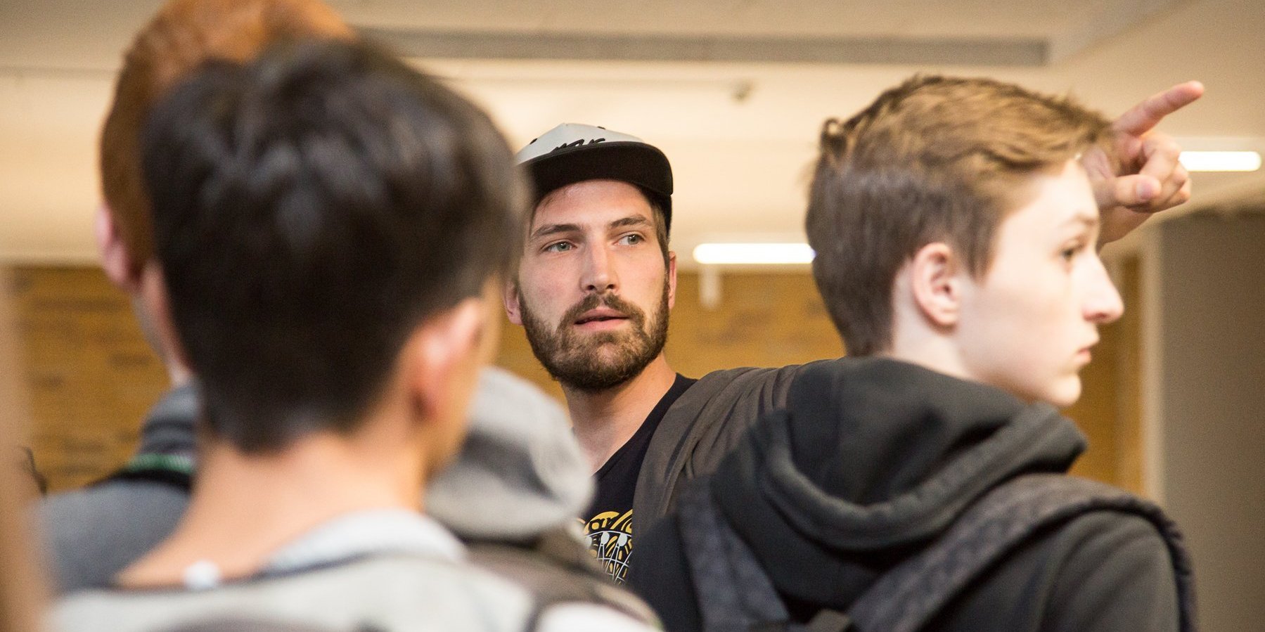 Ein studentischer Studienberater zeigt zwei Studierenden mit dem Zeigefinger etwas