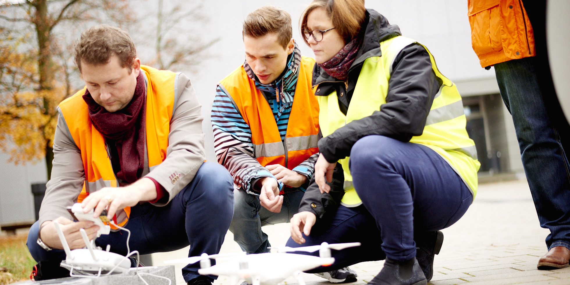 drei Personen in der Hocke vor einer Drohne