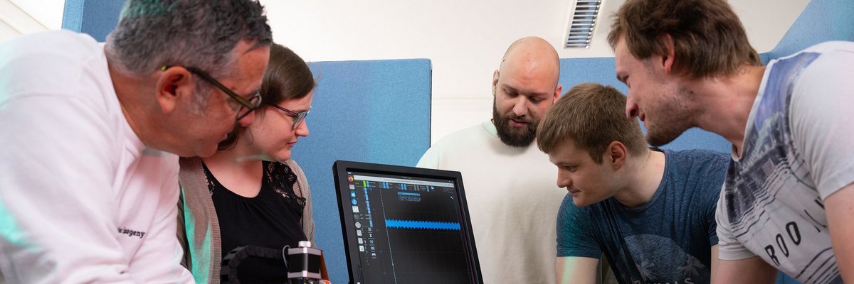Team vor steht rund um einen Arbeitsplatz mit Compter