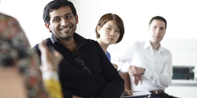 Sitting, smiling person, in the background two other persons