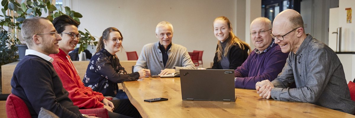 Mitglieder des studentischen Projektbüros sitzen rund um einen Konferenztisch mit Laptop.