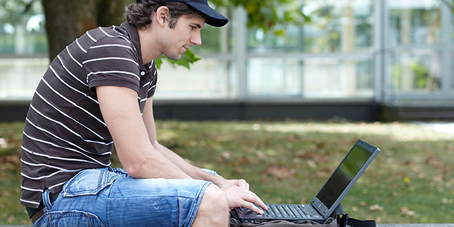 Student am Laptop auf dem Campus Darmstadt, vor dem C3 Hochhaus