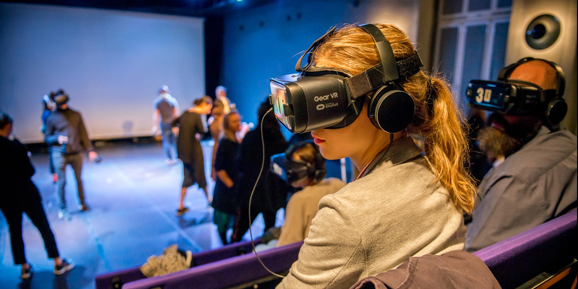 Augmented Reality - Studierende mit Virtual Reality Brillen. Sitzend in Vorlesungsreihen und "tanzend" im Raum