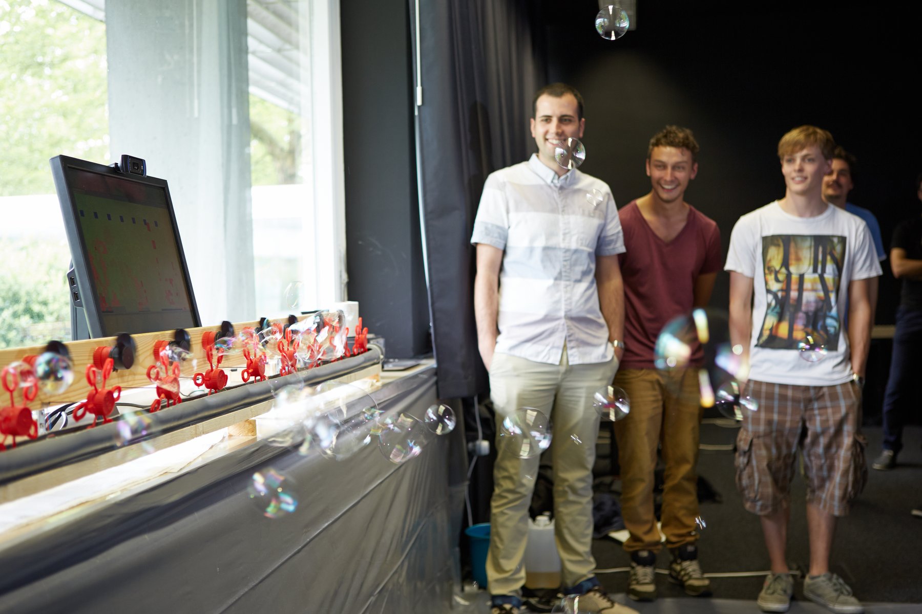 four people watching soap bubbles rise